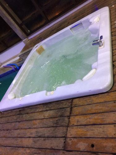 a bath tub filled with green water on a wooden floor at Flat em Gramado in Gramado