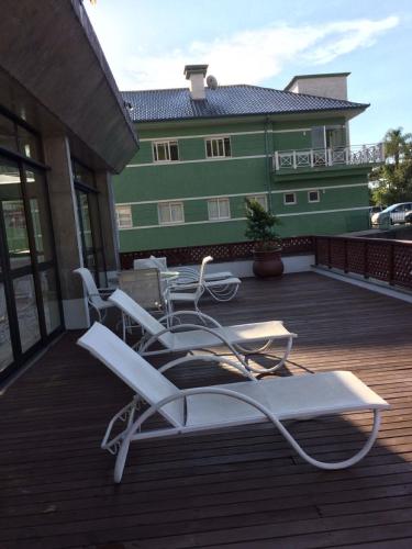 a group of chairs on a deck with a building at Flat em Gramado in Gramado