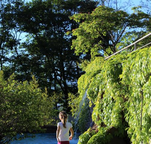 a woman walking down a path next to a river at Gartenresidence Stephanie by Hotel Rotwand in Laives