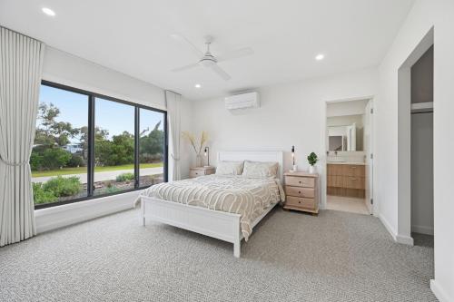 a white bedroom with a bed and a large window at Inverloch Seaside Escape in Inverloch