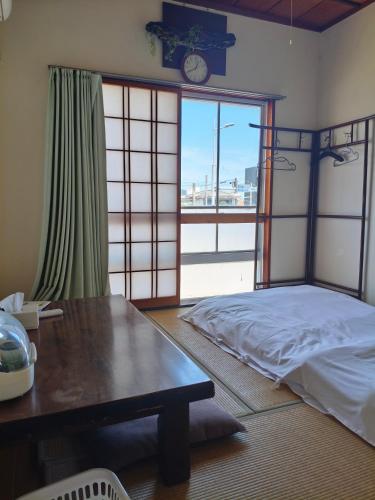 a bedroom with a bed and a table and a window at Guest House Aki in Nichinan
