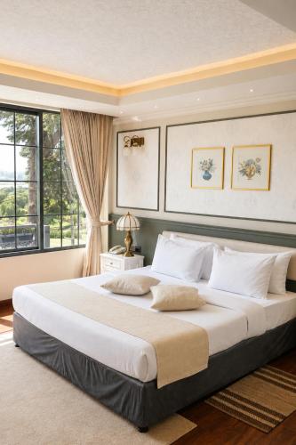 a large bed in a bedroom with a large window at Royal Lake Hotel in Nuwara Eliya