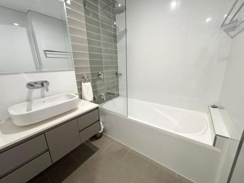 a white bathroom with a sink and a bath tub at Arizons in South West Rocks