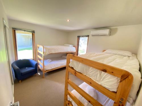 a bedroom with two bunk beds and a blue chair at Blue Sky Lodge in Dinner Plain