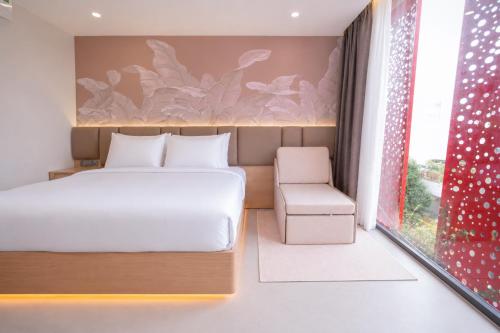 a bedroom with a bed and a chair and a window at Y Hotel Phan Đình Phùng in Can Tho