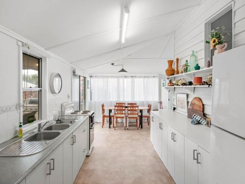 a kitchen with white cabinets and a dining room at River Cottage in Mylestom