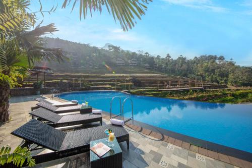 a pool with chairs and a table next to a mountain at Pu Luong EcoLuxe Resort & Spa in Pu Luong