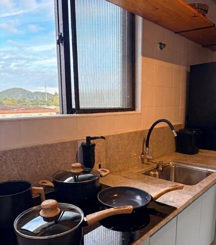 a kitchen with two pots and pans on a stove at Apartamento Centro Bertioga Casal e Família - Ar Condicionado - Praia da Enseada in Bertioga