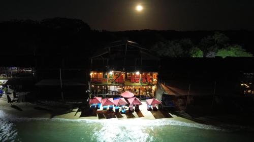 a building with tables and umbrellas next to the water at night at Ecohotelhector in Playa Blanca