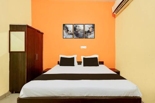 a bedroom with a large bed with an orange wall at Hotel O Royal Inn Hotel in Hāpur