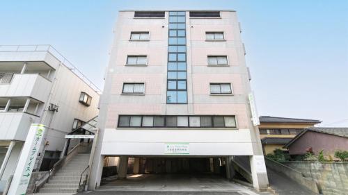 ein hohes rosafarbenes Gebäude mit einer Garage in der Unterkunft HOTEL Calmplace in Kanda