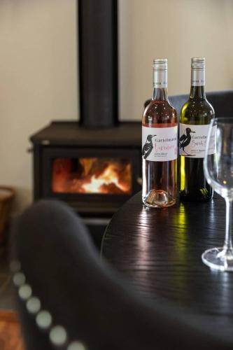 two bottles of wine on a wooden table with a fireplace at Gartelmann Studio at Gartelmanns Wines in Rothbury
