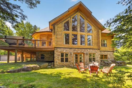 a log home with a deck and chairs in the yard at Fiddler Lake Resort - Deer 30 in Mille-Isles