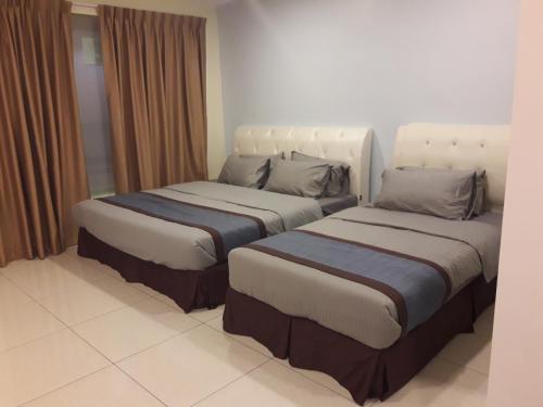two beds sitting next to each other in a room at De Benz Inn in Malacca