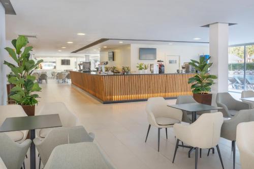 a restaurant with tables and chairs and a bar at SOL by Meliá Palmanova Mallorca in Palmanova