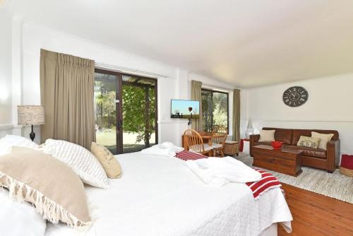 a bedroom with a large white bed and a living room at Olive Grove 1 Studio in Pokolbin