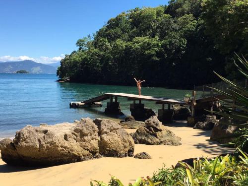 a person standing on a dock in the water at Bonito Paraiso Ilha Grande in Abraão