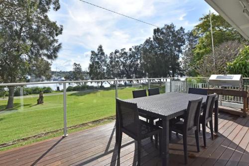 a table and chairs on the deck of a house at Wangi Lakehouse in Wangi Wangi