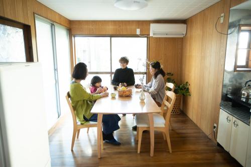 a group of people sitting around a table in a kitchen at 宇佐神宮近く- 神さまと仏さまと kamisama to hotokesama to in Nagasu