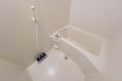 a bath tub with a shower head and a sink at R Hotel - Vacation STAY 19199 in Chiba