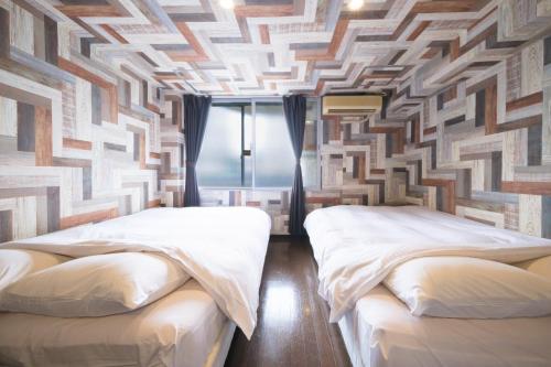 two beds in a room with a patterned wall at R Hotel - Vacation STAY 19198 in Chiba