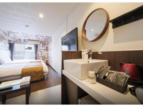a bathroom with a sink and a bed and a mirror at R Hotel - Vacation STAY 19692 in Chiba