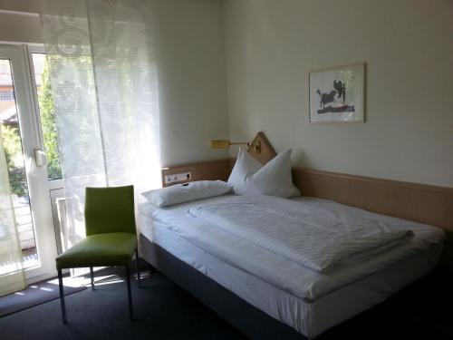 ein Schlafzimmer mit einem Bett, einem Stuhl und einem Fenster in der Unterkunft Hotel Garni Sand in Tübingen