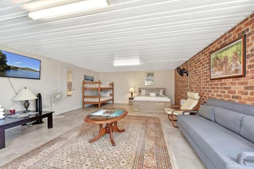 a living room with a couch and a brick wall at Noble Willow Studio Lovedale. A Cosy Unique Wine Country Refuge in Lovedale