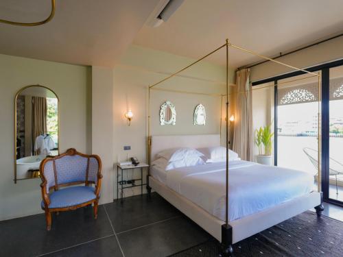 a bedroom with a canopy bed and a chair at Amdaeng Bangkok Riverside Hotel in Bangkok