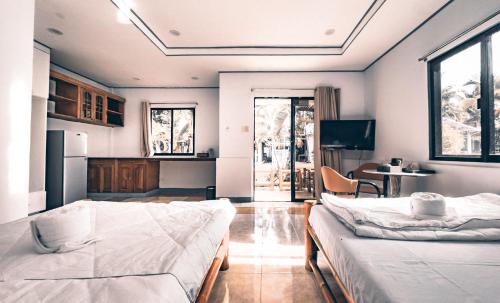 a bedroom with two beds and a kitchen with a table at Dumaguete Dive Center in Mojon