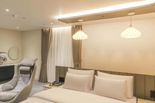 a hotel room with a bed and a chair at 주노 호텔 in Tujŏng-dong
