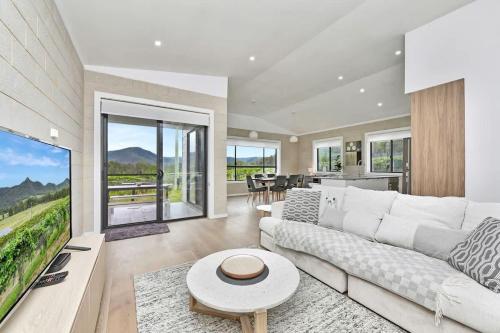 a living room with a white couch and a table at Somerville Wines Lux Escape 3-Bedroom Cottage Near Broke Wineries in Broke