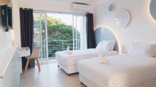 two white beds in a room with a window at The Room Hotel in Ban Nong Puk