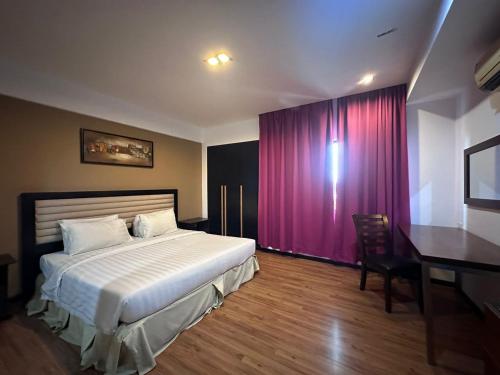 a bedroom with a bed and a desk and a purple curtain at Likas Square - KK Apartment Suite in Kota Kinabalu