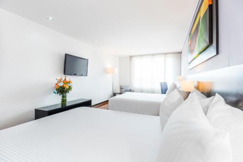 a hotel room with two beds and a tv at One Sixteen Hotel in Bogotá