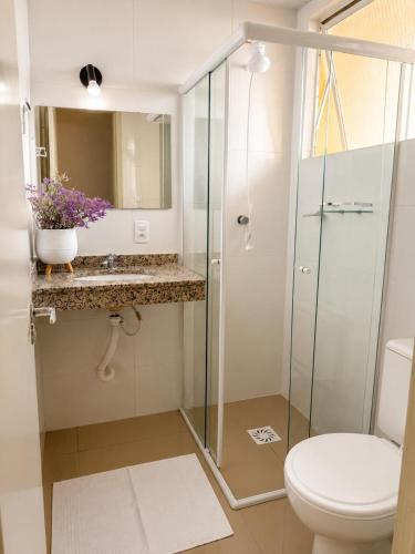 a bathroom with a toilet and a glass shower at Casa Da Praia Apart Hotel in Florianópolis