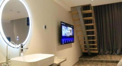 a bathroom with a mirror and a tv on the wall at Qingdao Elegance Hotel in Qingdao