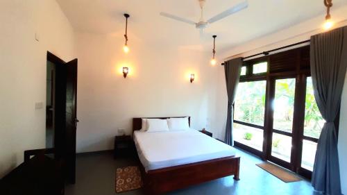 a bedroom with a bed and a large window at Turtle Point Homestay - BB, Fast Wi-Fi, AC in Batigama