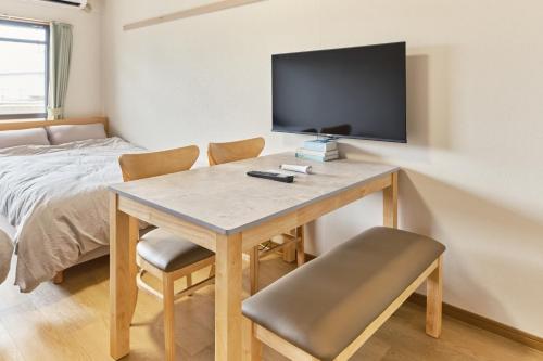 a room with a desk with a television and a bed at Green hills 102 in Kumamoto