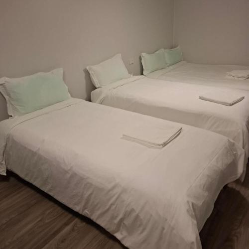 two beds in a room with white sheets and pillows at 2 Bedroom garden chalet in Rotorua