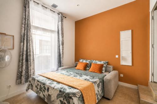 a bedroom with a bed with orange walls and a window at Studio narbonne in Narbonne