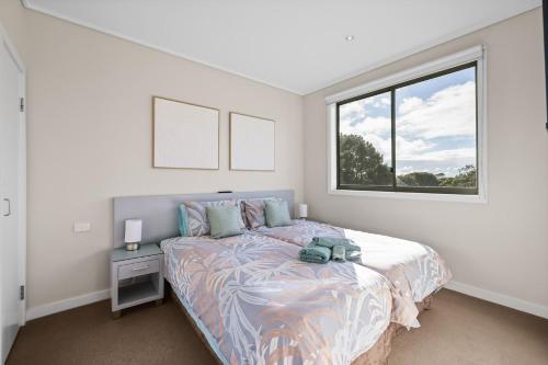 a white bedroom with a bed and a window at Potters Hill Haven in San Remo