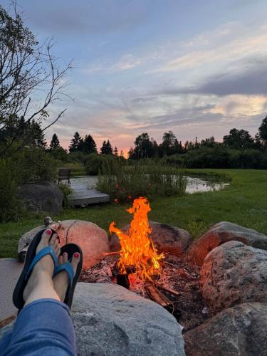 a person sitting on a rock next to a fire at The Alpine Suite | Walk to Downtown & Rangeley Lake Beach in Rangeley