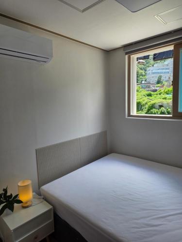 a white room with a bed and a window at Aju Good House 아주굿하우스 in Geoje
