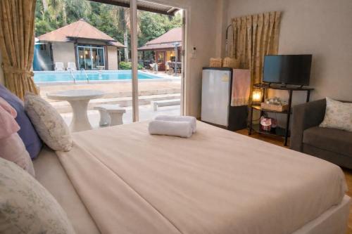 a bedroom with a bed and a tv and a window at The Scarecrow House in Ban Doem Bang (1)