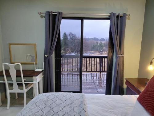 a bedroom with a bed and a desk and a window at Underwood Country Manor in Underberg