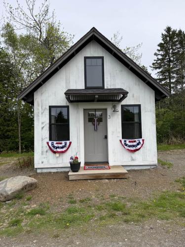 a white house with a porch and a door at The Evergreen | Walk to Rangeley Lake, Sled & ATV Access in Rangeley