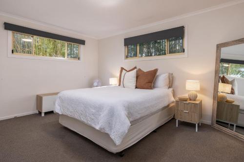 a white bedroom with a bed and a mirror at Sunset Palms in Smiths Lake