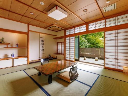 a room with a table and chairs and a large window at Suwa Grand Shrine Kameya Inn in Shimo-suwa