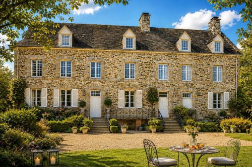 an old stone house with a table in front of it at Chateau d'Isigny - Normandie - Country House in Isigny-le-Buat